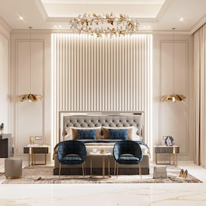 May include: A luxurious bedroom featuring a tufted headboard, two navy blue velvet chairs, and a gold leaf chandelier. The room has two gold accent side tables, a matching vanity, and two pendant lights. The walls are a light beige color.