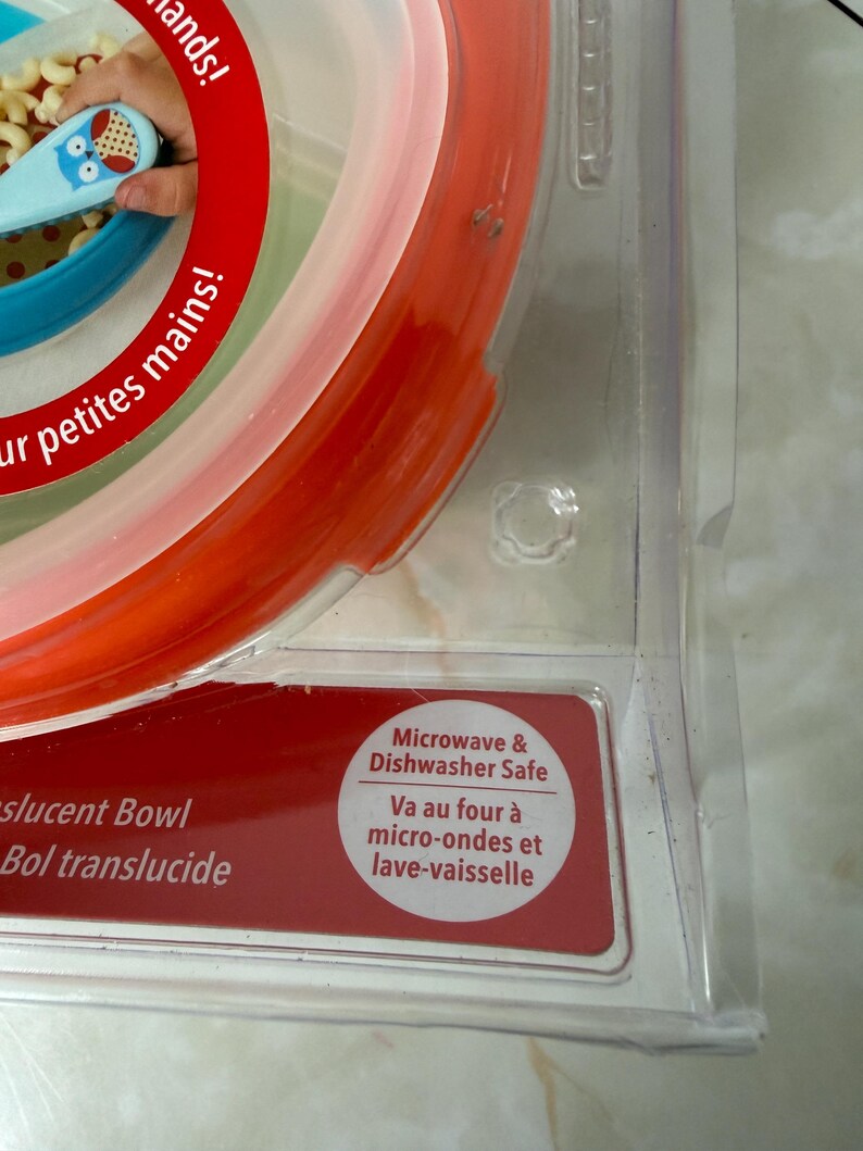 May include: A translucent bowl with red, white, and blue sections. The packaging includes the text "Microwave & Dishwasher Safe". The bowl is designed for small hands.