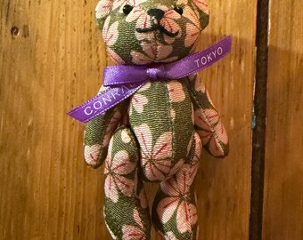Conrad Tokyo branded teddy bear souvenir made from kimono-style Japanese fabric. Features original purple ribbon printed “Conrad Tokyo.”