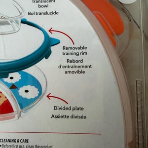 May include: A baby feeding set with a translucent bowl, a removable training rim, and a divided plate. The plate features a blue and white owl design. The packaging includes cleaning and care instructions.
