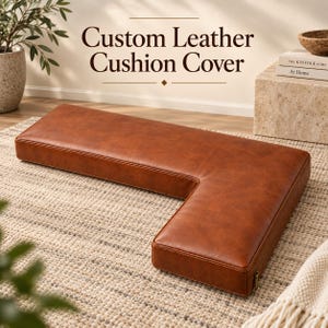 May include: An L-shaped custom leather cushion cover in a rich brown tone with visible stitching along the edges. The text Custom Leather Cushion Cover is displayed above the cushion. The cover features a zipper closure on the side panel.