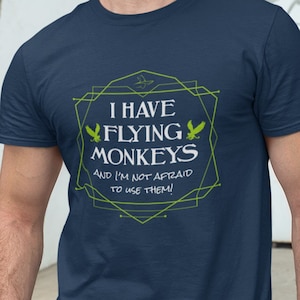 May include: A navy blue t-shirt with a green geometric design and the text "I have flying monkeys and I'm not afraid to use them!"