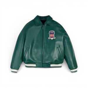 K&ouml;nnte beinhalten: Dunkelgr&uuml;ne Leder-Bomberjacke mit Rei&szlig;verschluss und klassischem Kragen. Die Jacke hat einen Aufn&auml;her auf der Brust mit einem patriotischen Design und dem Markennamen. Die Manschetten und der Saum haben wei&szlig;e und marineblaue Streifen.