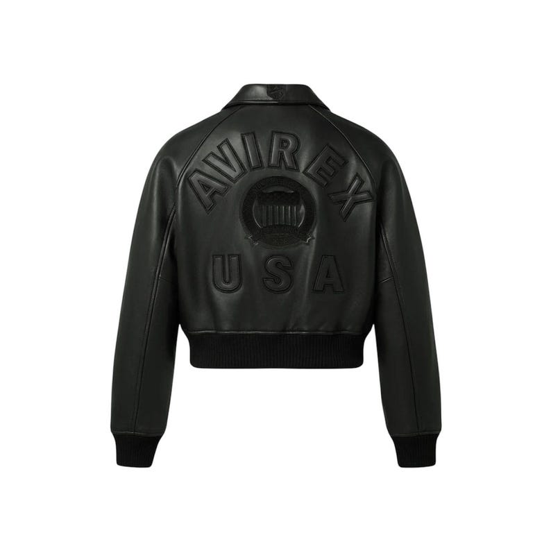 May include: Black leather bomber jacket with the embossed text "AVIREX USA" on the back. The jacket features a ribbed hem and cuffs, a classic collar, and a cropped fit. A stylish outerwear piece.