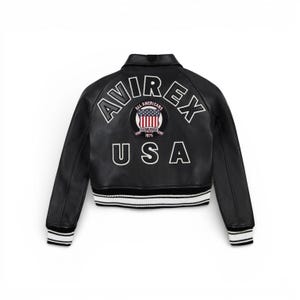 May include: Black leather jacket with white and black striped trim at the waist and cuffs. The back features the word "AVIREX" above a circular patch with the American flag and the word "USA" below.