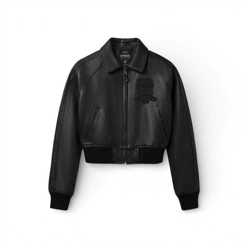 May include: Black leather bomber jacket with a zip-up front, collar, and ribbed cuffs and hem. Features a small patch on the chest and the brand name on the collar. A classic outerwear piece.