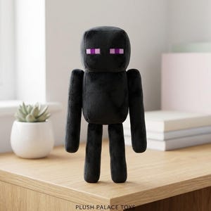 May include: A black plush toy of a Minecraft Enderman character, standing on a wooden surface. The toy has a blocky head with purple eyes and a rectangular body. The words "PLUSH PALACE TOYS" are at the bottom.