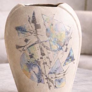 Può includere: Un vaso in ceramica beige con un design astratto. Il vaso ha una forma ovale ampia con un'apertura leggermente svasata. Il design include forme geometriche in blu, giallo e grigio, con linee nere. Adatto per l'arredamento della casa.