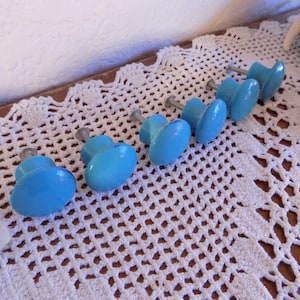 May include: Seven blue ceramic cabinet knobs with silver metal screws. The knobs are round and have a smooth, glossy finish.