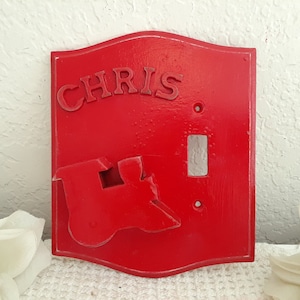 May include: Red light switch cover with a raised, stylized train design and the name "CHRIS" in raised letters.