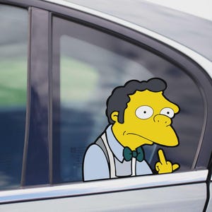 May include: A car window sticker featuring Moe Szyslak from The Simpsons, depicted with a yellow complexion, black hair, and a green bow tie, giving the middle finger. The sticker is a humorous depiction of the cartoon character.