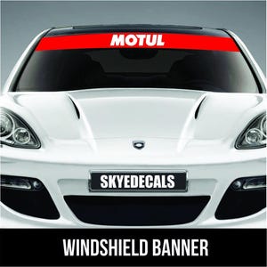 May include: A white car with a red windshield banner that reads "MOTUL" in white letters. Below the windshield is a license plate that reads "SKYEDECALS". The bottom of the image has the text "WINDSHIELD BANNER".