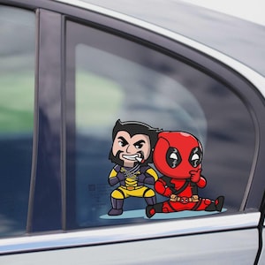 May include: A car window decal featuring cartoon versions of Wolverine in a yellow and blue costume and Deadpool in a red suit. The characters are posed together, with Deadpool sitting and Wolverine standing.