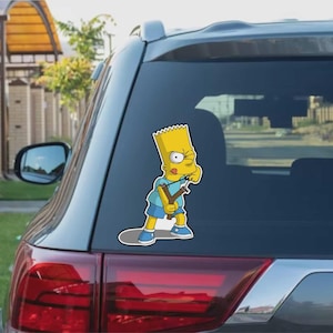 May include: A vinyl decal featuring Bart Simpson from The Simpsons cartoon. Bart is depicted in his signature yellow skin, blue shorts, and a light blue shirt, holding a slingshot. The decal is applied to the rear window of a car.