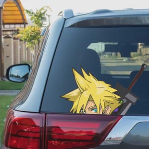 May include: A car window decal featuring a cartoon character with spiky yellow hair and blue eyes, peeking out from behind a large black sword. The decal is applied to the rear window of a gray car.