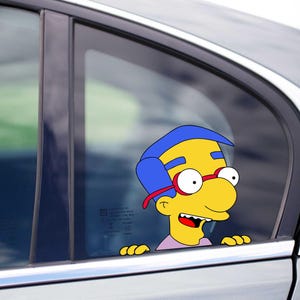 Peut inclure: Un autocollant de fenêtre de voiture représentant Milhouse Van Houten des Simpson. Le personnage a la peau jaune, les cheveux bleus, des lunettes rouges et une chemise rose. L'autocollant est placé sur une vitre de voiture.