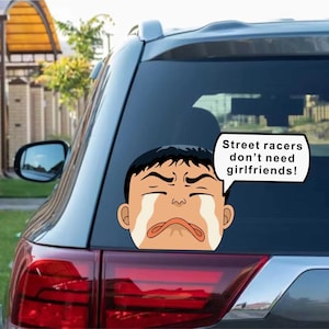 Può includere: Un adesivo per auto con l'immagine di un personaggio dei cartoni animati che piange con il testo "Street racers don't need girlfriends!" in un fumetto. L'adesivo è posto sul lunotto posteriore di un'auto.