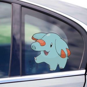 May include: A light blue cartoon elephant sticker with orange details is attached to a car window. The sticker, a character from a popular animated series, is smiling. The car window is framed by a black border.