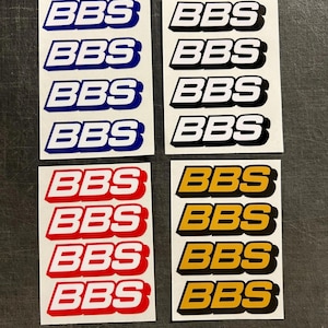 May include: Four sets of BBS stickers in different colour schemes: blue and white, black and white, red and white, and gold and black. Each set has four stickers with the BBS logo in a bold, sans-serif font.
