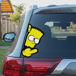May include: A yellow vinyl car sticker depicting Bart Simpson giving the middle finger. The sticker shows Bart's head and arm in a cartoon style, with black outlines and white eyes. The sticker is affixed to the rear window of a grey car.
