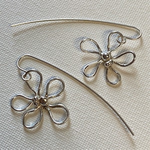 May include: A pair of silver dangle earrings with a flower design. Each earring features a five-petal flower with a small bead in the center.