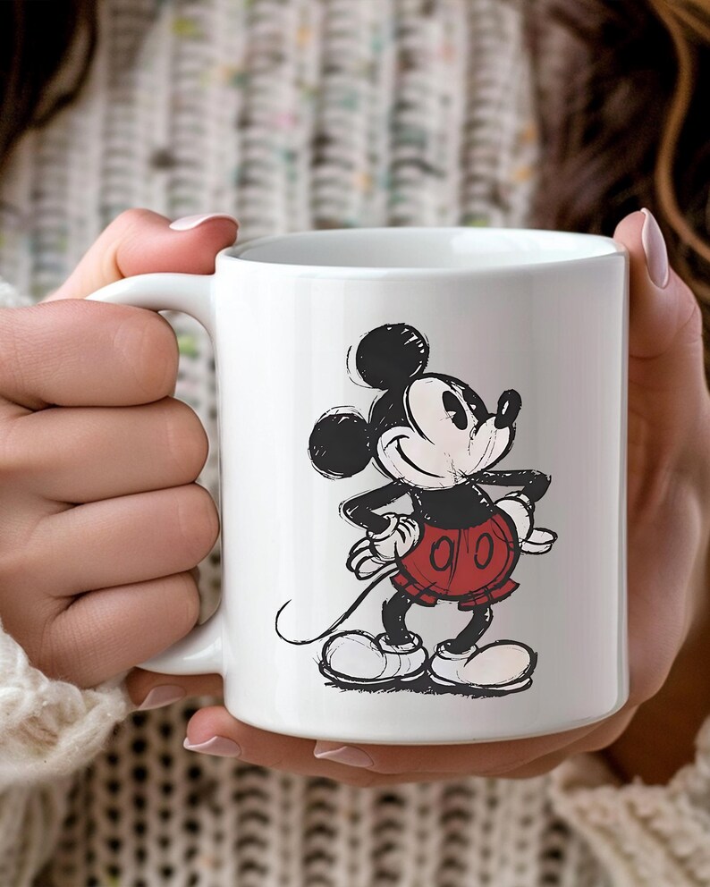 May include: A white ceramic mug with a black handle and the text "But First, Coffee" in a black, handwritten-style font. The mug is on a white surface.