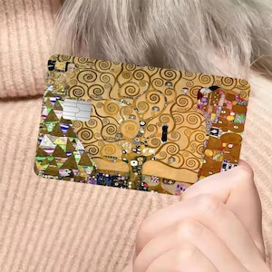 May include: A rectangular card featuring a reproduction of Gustav Klimt's "The Tree of Life" painting. The card has a gold and brown color scheme with intricate swirling patterns and geometric shapes. A silver magnetic stripe is visible.