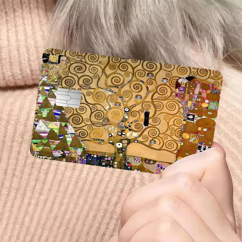 May include: A rectangular card featuring a reproduction of Gustav Klimt's "The Tree of Life" painting. The card has a gold and brown color scheme with intricate swirling patterns and geometric shapes. A silver magnetic stripe is visible.