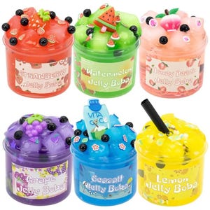 May include: Six clear plastic containers filled with colorful jelly slime, each topped with themed charms and black beads. The labels read Strawberry, Watermelon, Honey Peach, Grape, Seasalt, and Lemon Jelly Boba, featuring matching fruit or drink-themed decorations.