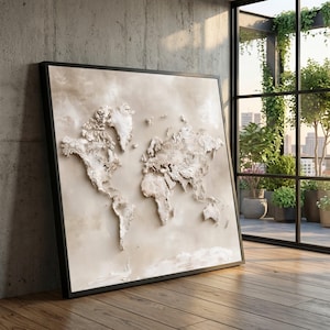 Può includere: Un'opera d'arte da parete quadrata che presenta una mappa del mondo tridimensionale in tonalità beige e crema. I continenti sono resi con un effetto a rilievo strutturato su uno sfondo neutro, il tutto racchiuso in una sottile cornice nera.