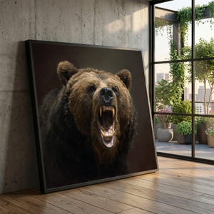 Op de afbeelding: Een ingelijste canvas print met een close-up van een grizzlybeer met zijn bek open, zijn tanden tonend. De beer heeft bruine vacht en staat tegen een donkere achtergrond. De lijst is zwart.