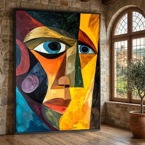May include: Abstract portrait painting with a black frame. The artwork features a stylized face with bold colors, including blue eyes, orange, yellow, and green. The painting is displayed on a brick wall.