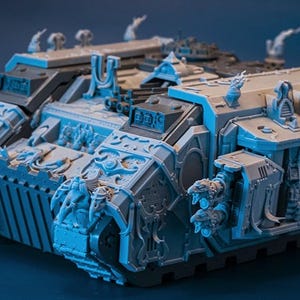 Peut inclure: Maquette de char miniature détaillée, grise et noire, avec des détails sculptés complexes. Le modèle présente des motifs ornés, notamment des figures et des éléments architecturaux, et est probablement un objet de collection ou de loisirs.