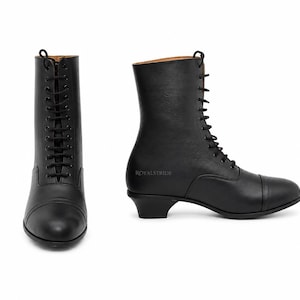 May include: A pair of black lace-up boots featuring a mid-calf height, a rounded toe cap, and a low block heel. The side of the boot displays the text ROYALSTRIDE in a subtle font. The design includes a full front lace closure with black laces.