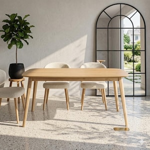 Puede incluir: Una mesa de comedor de madera clara con esquinas redondeadas y patas anguladas. Cuatro sillas con asientos texturizados de color claro rodean la mesa. Una gran planta en maceta negra y una ventana arqueada están en el fondo.