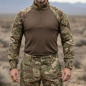 Puede incluir: Una persona con una camisa de combate de camuflaje con torso marrón y mangas largas, combinada con pantalones de camuflaje a juego. El atuendo está diseñado para actividades al aire libre y uso táctico.