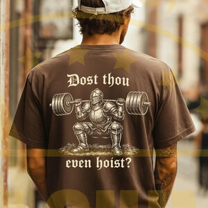 Puede incluir: Camiseta marr&oacute;n con un gr&aacute;fico de un caballero levantando pesas y el texto "Dost thou even hoist?". El caballero lleva una armadura y levanta una barra. La camiseta es de estilo casual.