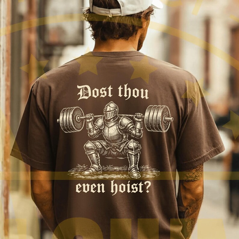 Puede incluir: Camiseta marr&oacute;n con un gr&aacute;fico de un caballero levantando pesas y el texto "Dost thou even hoist?". El caballero lleva una armadura y levanta una barra. La camiseta es de estilo casual.