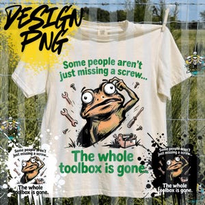 May include: Off-white t-shirt with a cartoon frog graphic. The frog is surrounded by tools and the text reads, "Some people aren't just missing a screw... The whole toolbox is gone." Design PNG text is in the upper left.