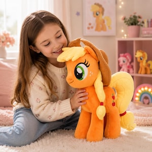 May include: An orange plush pony toy with a yellow mane and tail, wearing a brown cowboy hat. The pony features large green eyes, a blonde braided mane, and three red apple icons on its flank. The plush has a soft texture and stands upright.