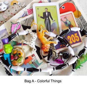 May include: A collection of colorful objects including a Dalmatian figurine, a toy cat, a green dinosaur, and a beaded necklace with black and white beads. There are also playing cards, a die, and a small sign with the number 205. The text "Bag A - Colorful Things" is at the bottom.