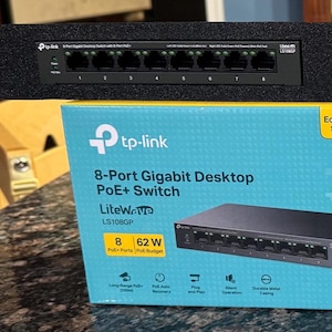 Peut inclure: Deux commutateurs Gigabit de bureau PoE+ à 8 ports noirs de tp-link sont affichés au-dessus de deux boîtes avec les mêmes informations sur le produit. Les boîtes sont de couleur sarcelle avec du texte blanc et un graphique de commutateur noir.