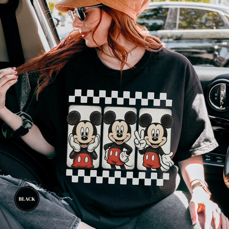 Puede incluir: Camiseta negra con un dise&ntilde;o de tres ilustraciones de Mickey Mouse. Cada Mickey Mouse est&aacute; en una pose diferente, con pantalones cortos rojos y guantes blancos. El dise&ntilde;o est&aacute; enmarcado por un patr&oacute;n de cuadros blancos y negros.
