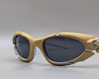 Oakley Plate Y2K Wraparound zonnebril – Goudkleurig montuur / Donkere glazen – Sportief design uit de jaren 2000