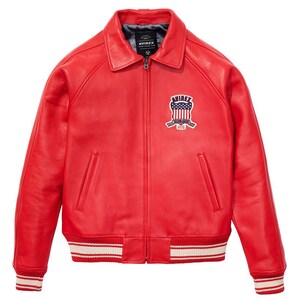May include: A bright red leather jacket with a zip-up front, collar, and ribbed cuffs and hem. The jacket features a patch with the text "AVIREX" and an American flag design on the chest. The cuffs and hem have white stripes.