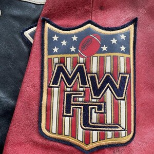 Peut inclure: Gros plan sur une veste universitaire rouge et noire avec un &eacute;cusson sur le th&egrave;me du football. L'&eacute;cusson repr&eacute;sente un ballon de football, des &eacute;toiles et les lettres "MW FC" dans un motif de bouclier. La veste a une texture semblable &agrave; du cuir.