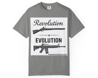 May include: Gray t-shirt with a white rectangle featuring the words "Revolution" and "Evolution" with illustrations of a musket and a modern rifle. The website address "POWDERANDLEAD.NET" is at the bottom.
