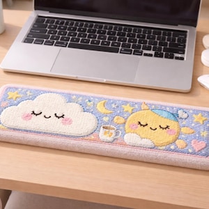 Peut inclure: Tapis de bureau rectangulaire bleu clair et rose avec un motif fantaisiste. Il présente un nuage souriant, un soleil avec un bonnet de nuit, des étoiles et un croissant de lune. Une petite tasse à café est également incluse dans le motif. Un ordinateur portable est en arrière-plan.
