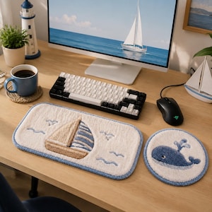 May include: A nautical-themed desk setup featuring a white and black keyboard, a black mouse, and a sailboat-themed mousepad. A blue mug with coffee sits next to a coaster. A small decorative lighthouse and sailboat are also present.