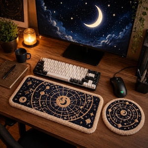 May include: A desk setup featuring a keyboard, mouse, and a celestial-themed desk mat and coaster. The navy blue mat and coaster have a beige border and a gold celestial design. A computer monitor displays a night sky scene.